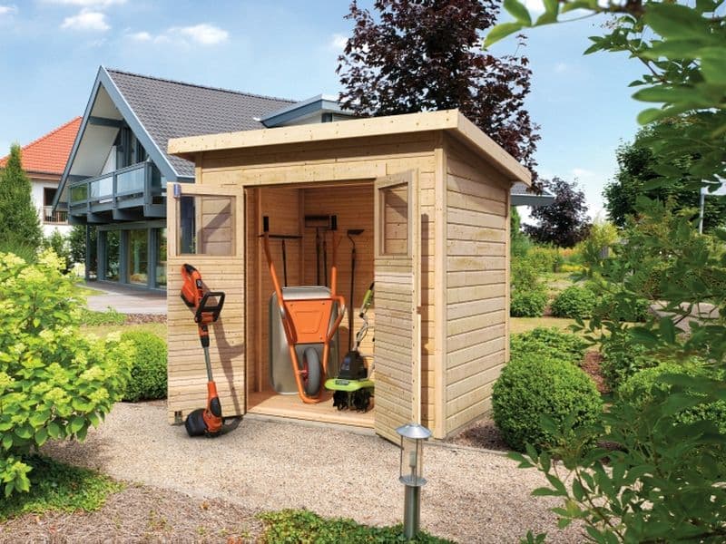 Dřevěný zahradní domek Karibu Merseburg s oražovým kolečkem opřeným o stěnu