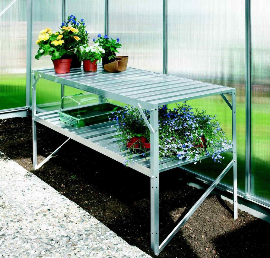 Regál s květinami a náčiním ve skleníku